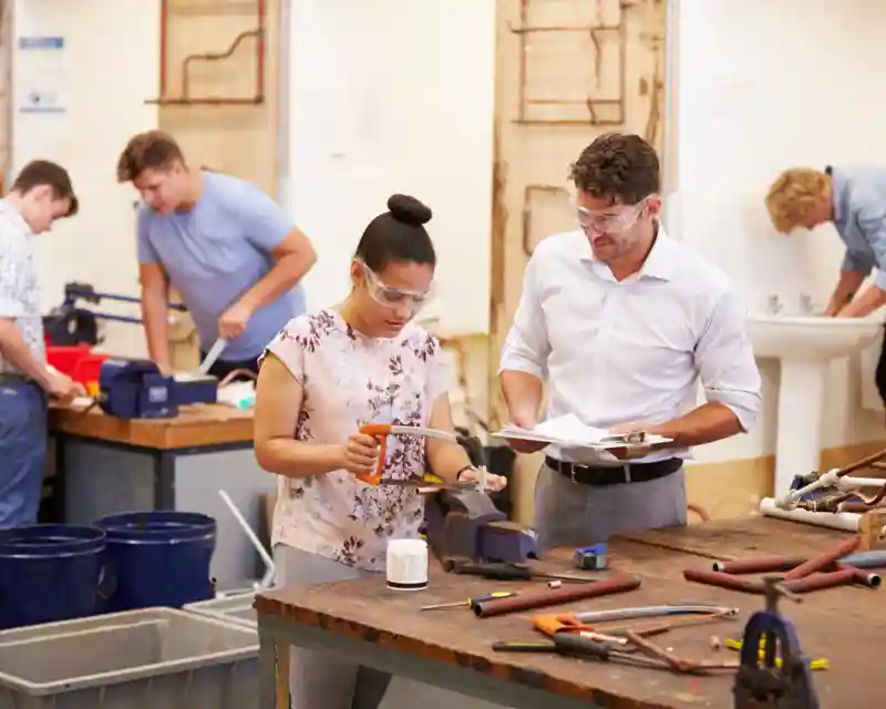 A picture showing a teacher teaching a female-looking student in a workshop.